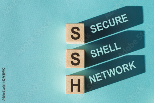 Wooden cubes building word SSH - (abbreviation Secure Shell Network) on light blue background. photo
