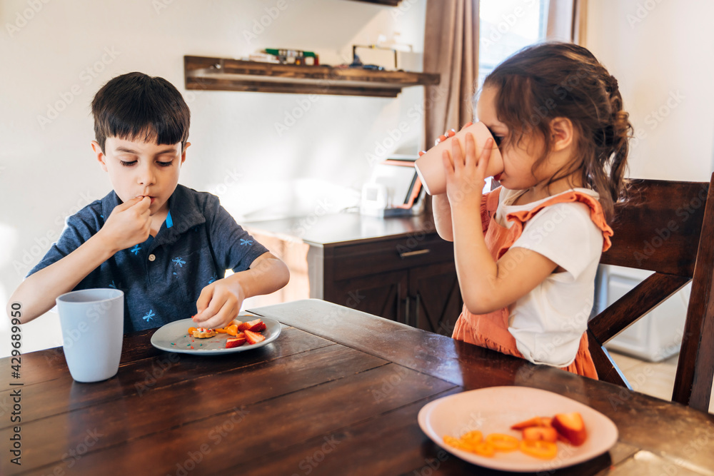 Brother and sister eating together at dining room table Brother and sister eating together at dining room table