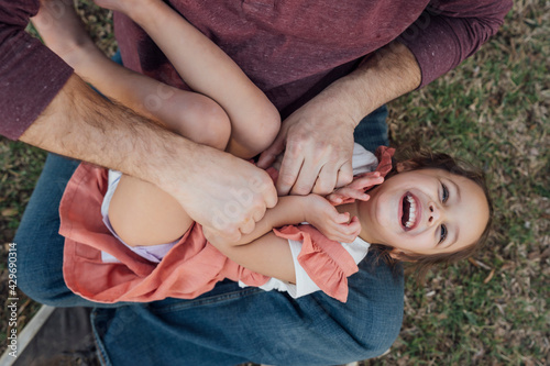 Принти на полотні Dad tickling laughing daughter in his lap