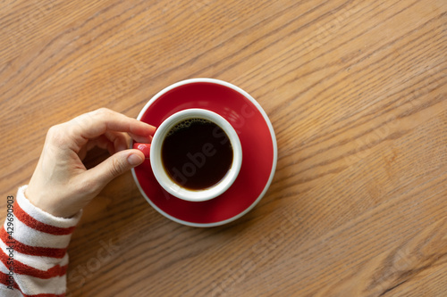 Women's hands holding a red cup of coffee. coffee shop, pastry shop for socializing and enjoying coffee, a breakfast drink. soft selective focus