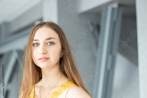 portrait of a beautiful young long blond hair and blue eyes woman in yellow blouse with building walls and posts background Free Download portrait of a beautiful young long blond hair and blue eyes woman in yellow blouse with building walls and posts background - GFXLoad