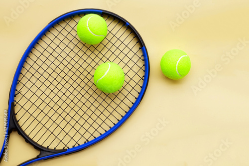 Tennis racket with balls on yellow background. © Bowonpat