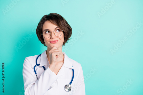 Photo portrait of smiling female doctor looking blank space wearing white uniform isolated bright teal color background