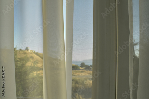 the folds on the transparent, light tulle, taken close-up and the mountains and the sea visible through it
