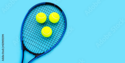 Tennis racket with balls on blue background. © Bowonpat