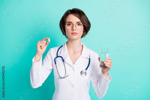 Photo portrait of female doctor keeping pills water glass treatment serious isolated vibrant teal color background