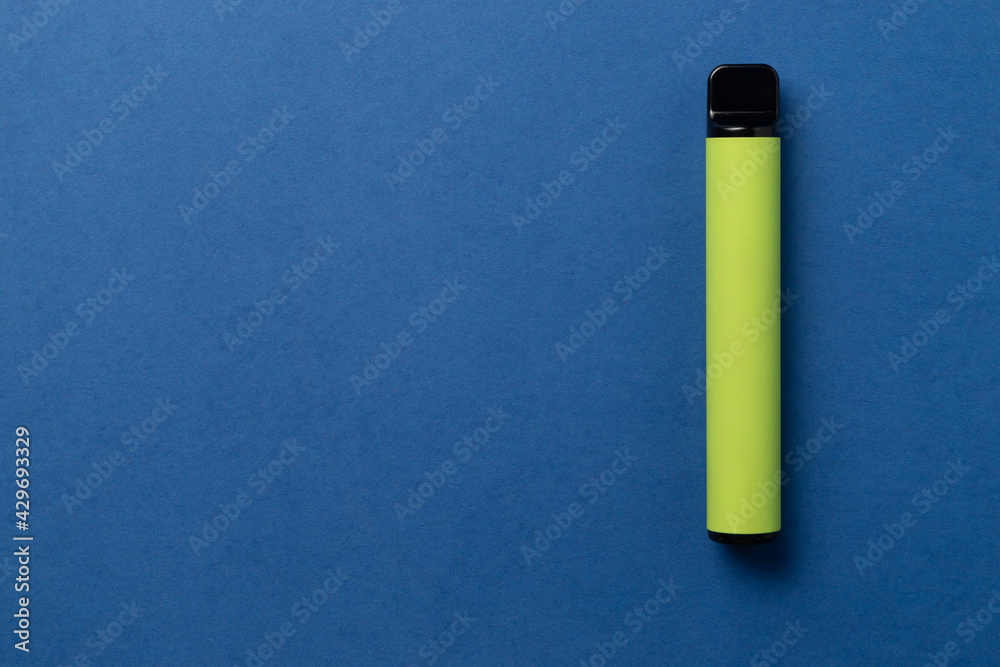 Disposable e-cigarette in green color on blue isolated background. The concept of modern smoking, vaping and nicotine. Top view Disposable e-cigarette in green color on blue isolated background. The concept of modern smoking, vaping and nicotine. Top view