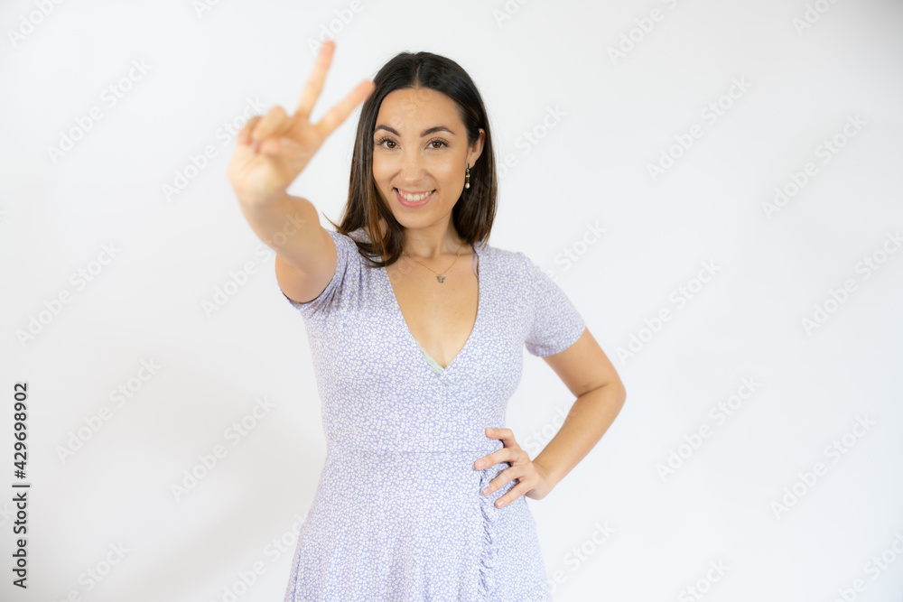 Young hispanic woman isolated showing victory sign and smiling broadly. Young hispanic woman isolated showing victory sign and smiling broadly.