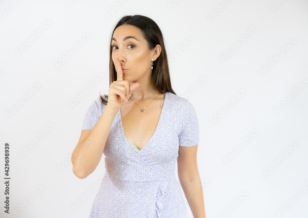 Portrait of beautiful and young brunette woman standing over isolated white background asking to be quiet with finger on lips. Silence and secret concept. Portrait of beautiful and young brunette woman standing over isolated white background asking to be quiet with finger on lips. Silence and secret concept.