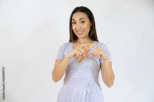 Young smiling woman making heart figure isolated over white background. Romantic concept.