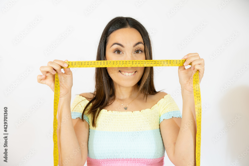 Closeup portrait of a happy young woman holding measuring tape Closeup portrait of a happy young woman holding measuring tape