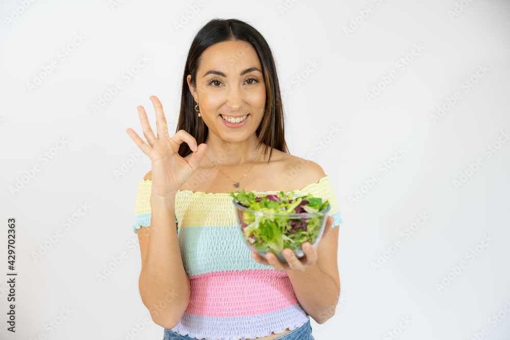 Portrait of a happy playful woman eating fresh salad from a bowl isolated over white background Portrait of a happy playful woman eating fresh salad from a bowl isolated over white background