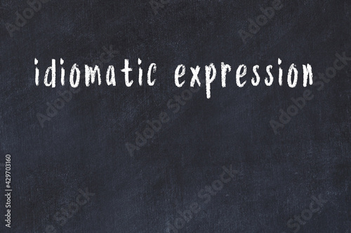 Black chalkboard with inscription idiomatic expression on in