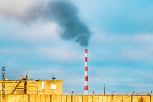 Ecological problem, environmental pollution, industrial zone with smoke from a pipe of a thermal power plant on a background of blue sky and sunset