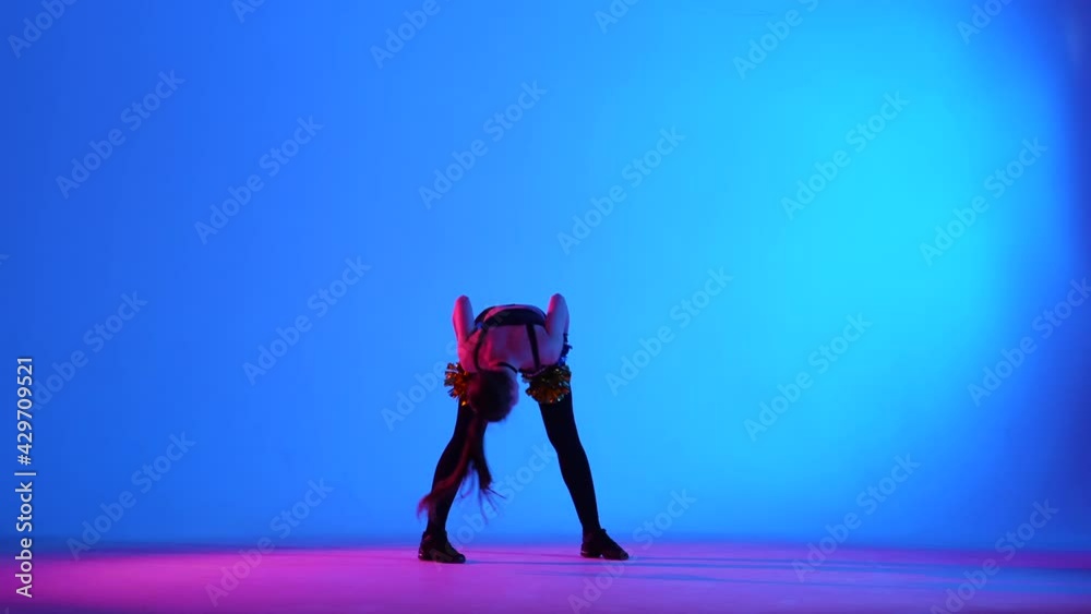 Energetic cheering dance performed by cute cheerleader with pompoms in hands against blue background, illuminated with pink light. Cheerleading, cheering sports team. Slow motion. Energetic cheering dance performed by cute cheerleader with pompoms in hands against blue background, illuminated with pink light. Cheerleading, cheering sports team. Slow motion.