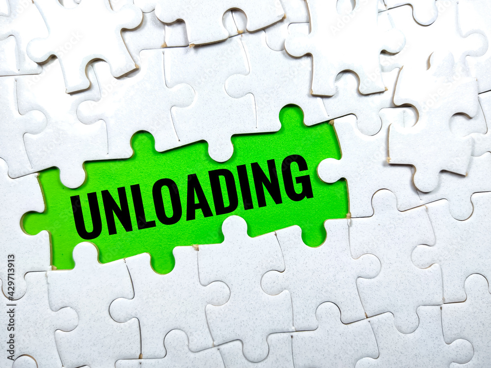 Selective focus.Word UNLOADING with jigsaw puzzle on green background. Selective focus.Word UNLOADING with jigsaw puzzle on green background.