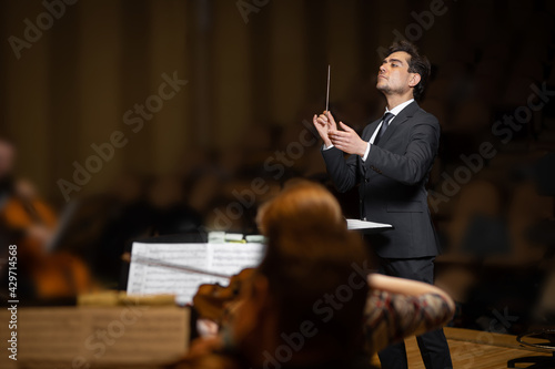 Foto Conductor of symphony orchestra with performers in background in concert hall