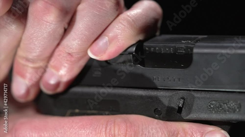 This close up video shows a detailed and slow motion view of hands cocking a gun and bullet shells flying out.