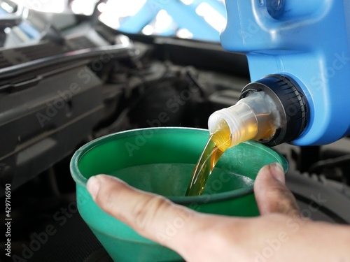 car mechanic replacing oil lubricant into engine a car at garage. 