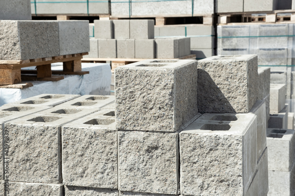 Stack of cement concrete Building cinder blocks brick on pallete in hardware store with decorative stone texture side Stack of cement concrete Building cinder blocks brick on pallete in hardware store with decorative stone texture side