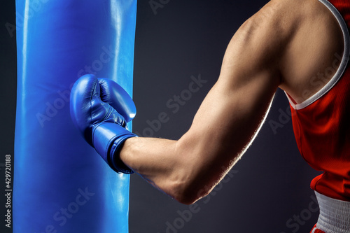 Boxer's hand in a blue boxing glove. A boxer strikes a punching bag.