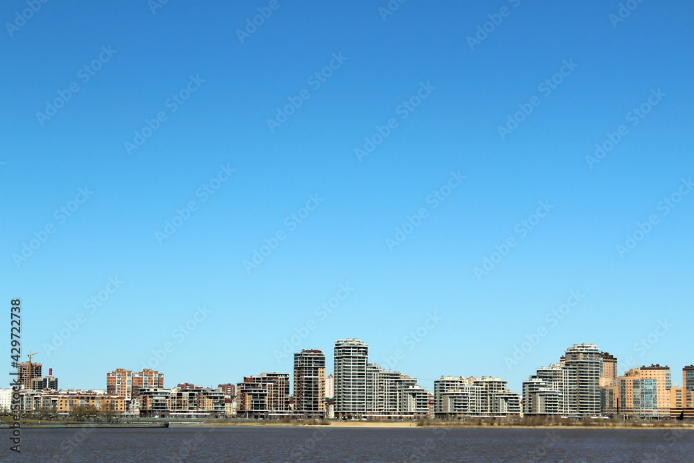 View of the city from the side of the river in early spring on a warm sunny day View of the city from the side of the river in early spring on a warm sunny day