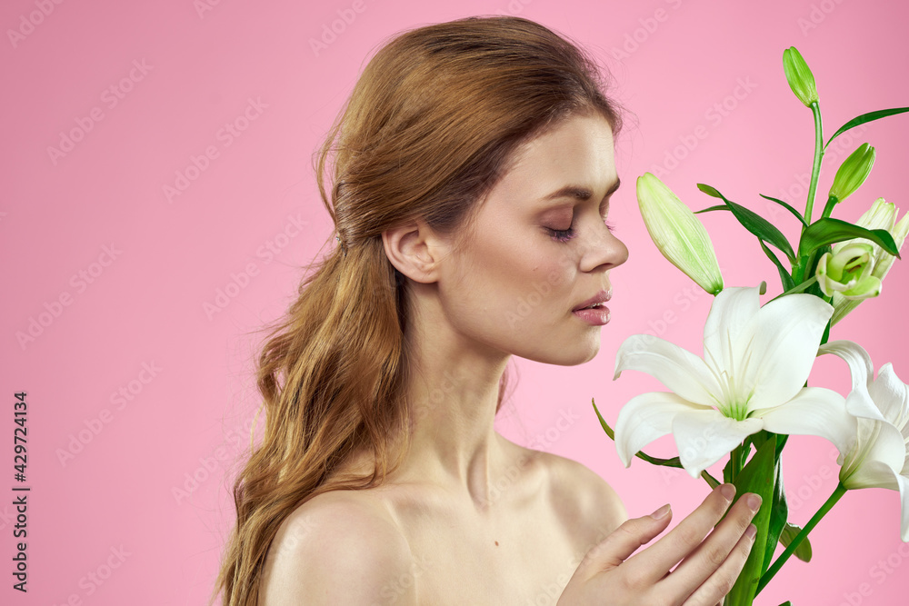 Portrait of a beautiful woman with white flowers in her hands on a pink background Copy Space cropped view