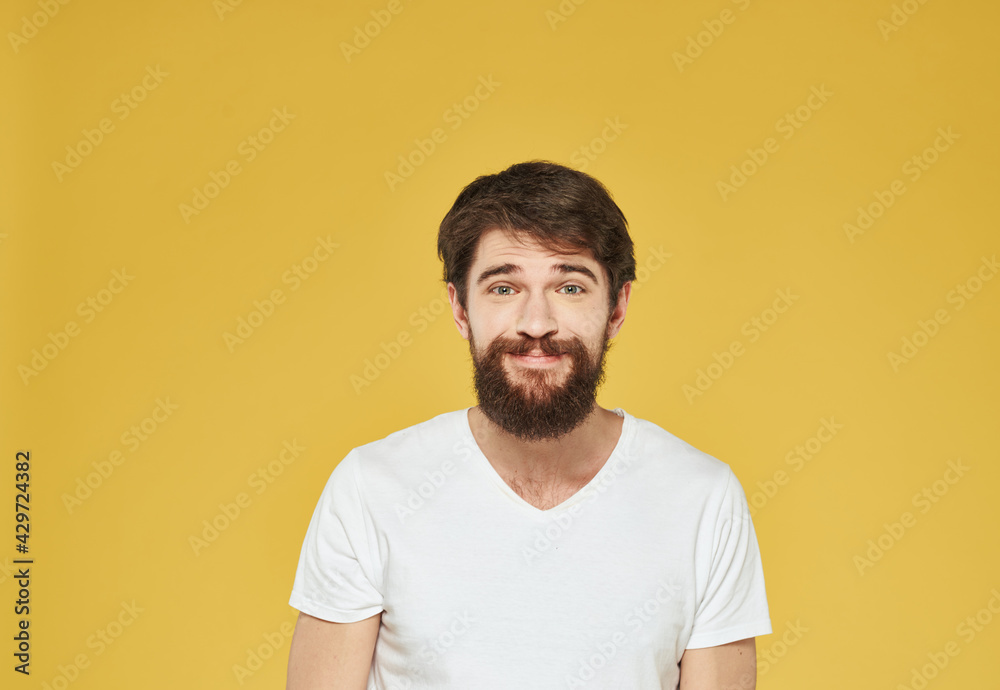 Portrait of a man bushy beard mustache white t-shirt yellow background cropped view Portrait of a man bushy beard mustache white t-shirt yellow background cropped view