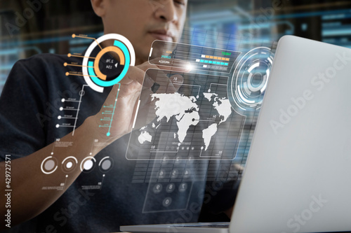 Asian man in a modern office touching futuristic computer virtual touch screen or augmented reality control panel while reviewing data on business administration.