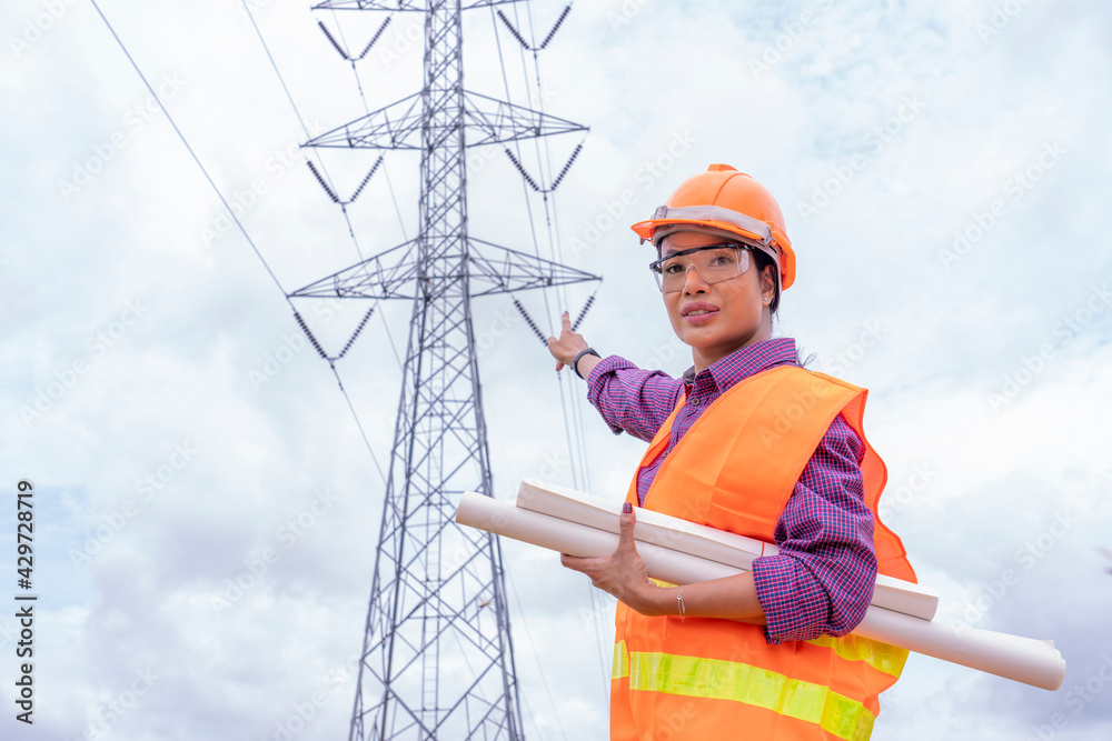 Woman engineers construction worker checking layout on digital ipad or computer. Foreman working  at construction Site with Electric Tower background