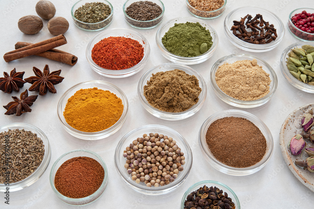 samples of different spices in glass bowls on a white background