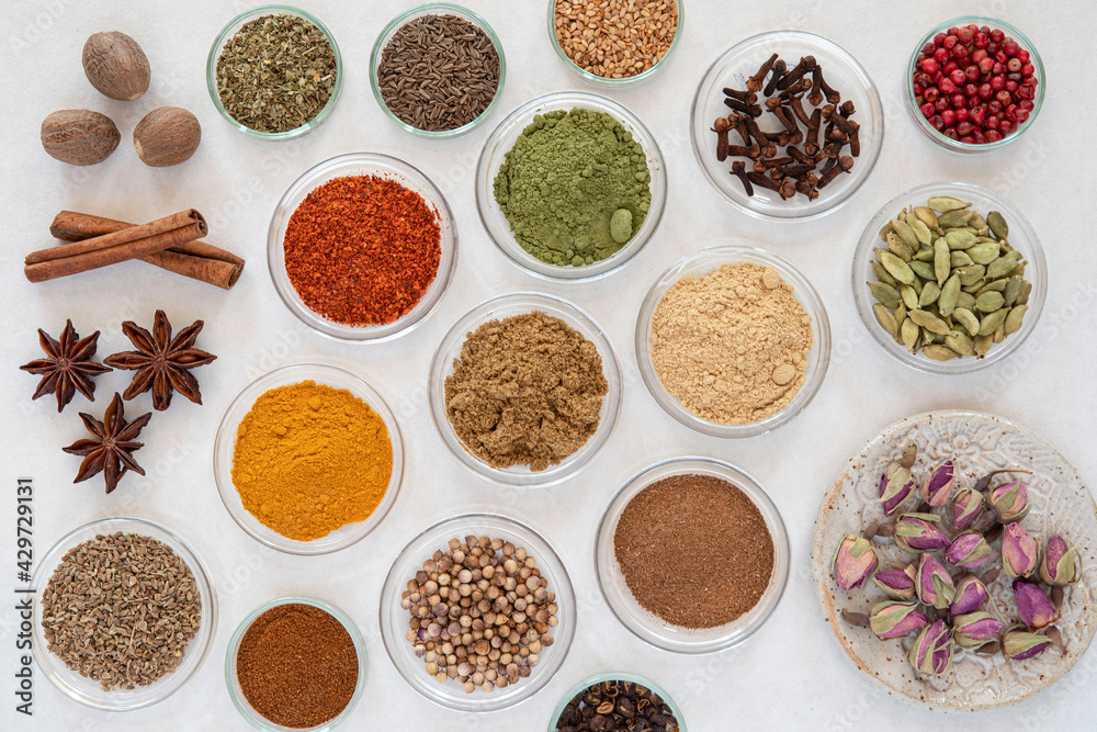 samples of different spices in glass bowls on a white background