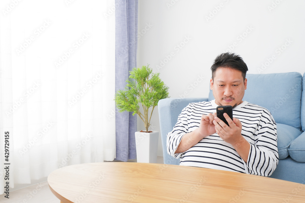 Fototapeta premium 部屋でスマホを使う男性