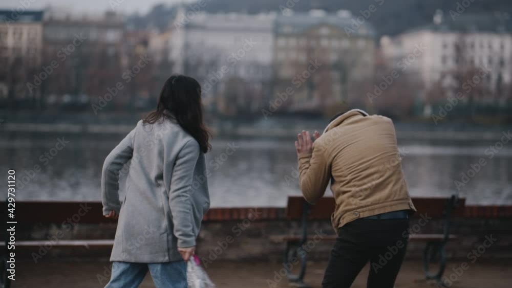 Quarrel on date on 8 march, valentine day or international women day. Young asian girl arguing with guy because of cheating. Woman screaming and beating man with bouquet of flowers for treason.