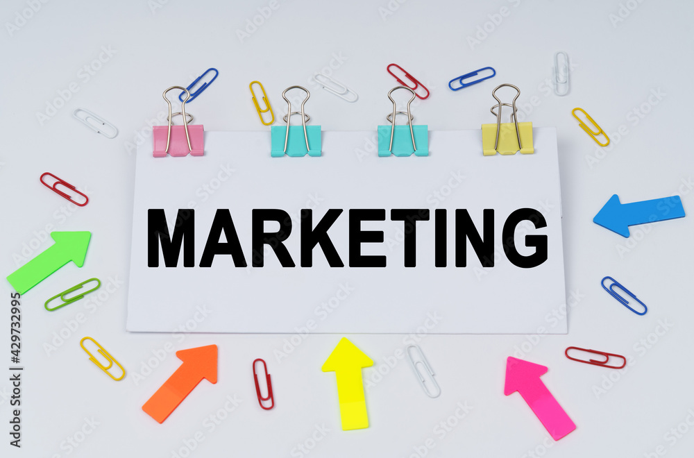 On the table there are paper clips and directional arrows, a sign that says - Marketing On the table there are paper clips and directional arrows, a sign that says - Marketing