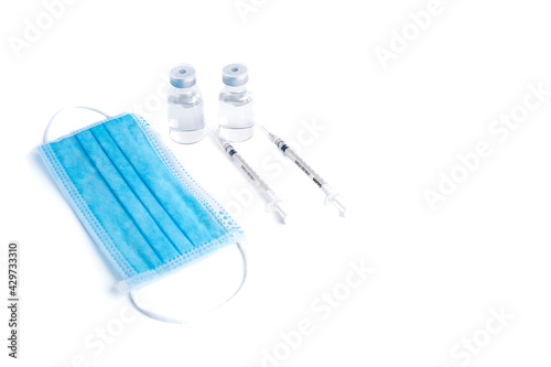 Empty bottle of vaccine with syringe and mask for hygiene injection. Pharmaceutical equipment protective infection of pandemic covid-19 virus  flu  disease. Isolated on white background  copy space.