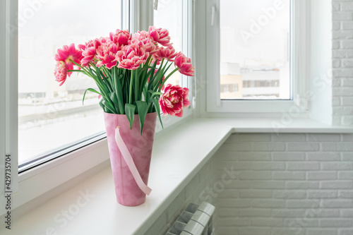 pink terry tulips in a basket stand on the windowsill
