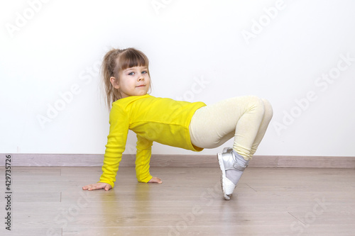 little girl in casual yellow clothes doing gymnastics at home
