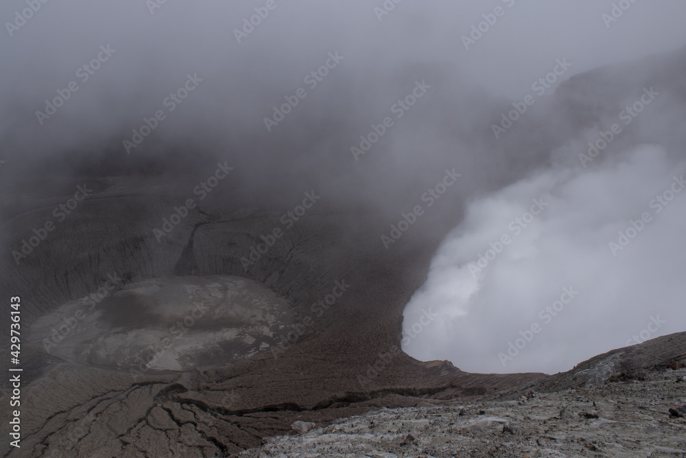 active crater of the turrialba volcano in the middle of a dark and cloudy day with an arid and desert landscape