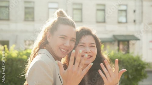 Happy lesbian couple posing for photohrapher. Girls showing engagement rings on hands enjoying romantic celebration. Together taking selfie, extremely happy. LGBT Pride Month, Gay Pride Symbol photo