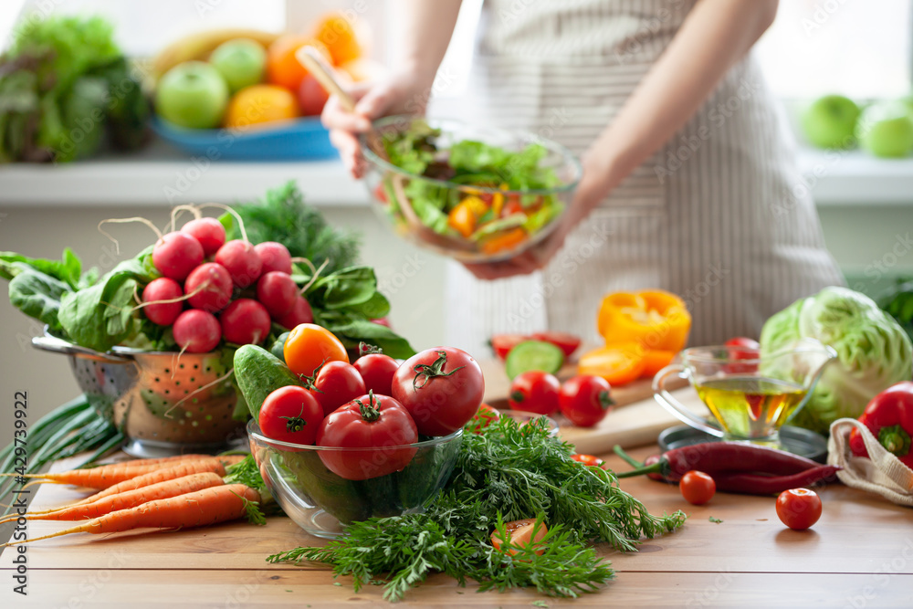 Beautiful young woman preparing delicious fresh vitamin salad. Concept of clean eating, healthy food, low calories meal, dieting, self caring lifestyle. Colorful vegetables, glass bowl. Close up Beautiful young woman preparing delicious fresh vitamin salad. Concept of clean eating, healthy food, low calories meal, dieting, self caring lifestyle. Colorful vegetables, glass bowl. Close up