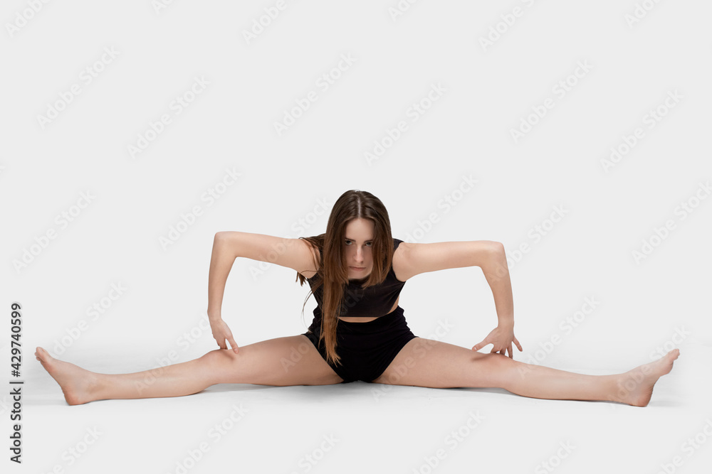 Young slim athletic girl, with long hair, in a black top and shorts, in the studio on a white background