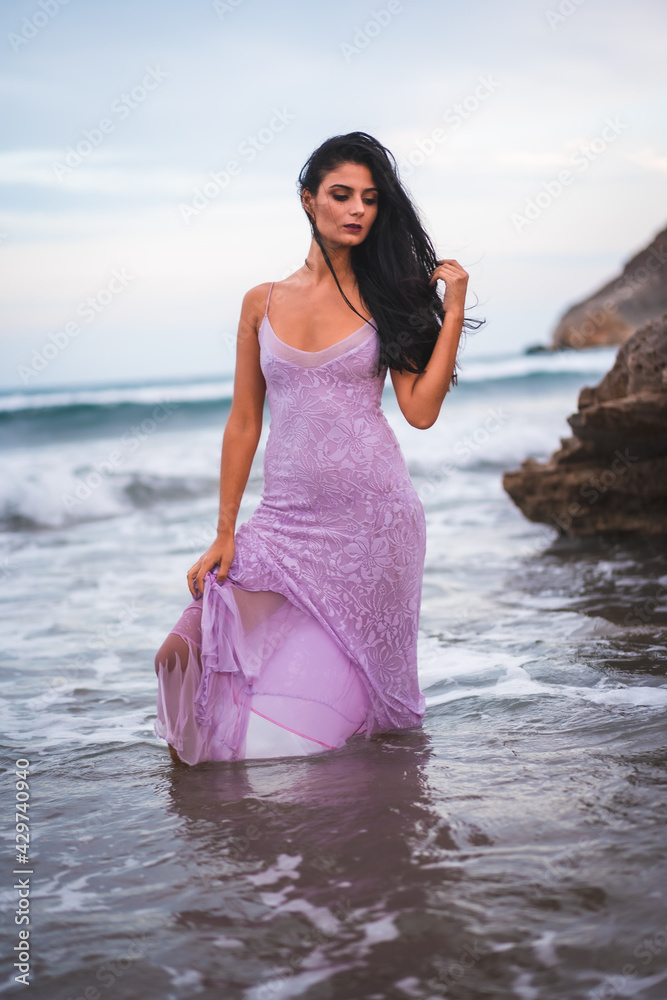 Caucasian brunette with a pink cloth dress, on the beach inside the sea enjoying the holidays Caucasian brunette with a pink cloth dress, on the beach inside the sea enjoying the holidays