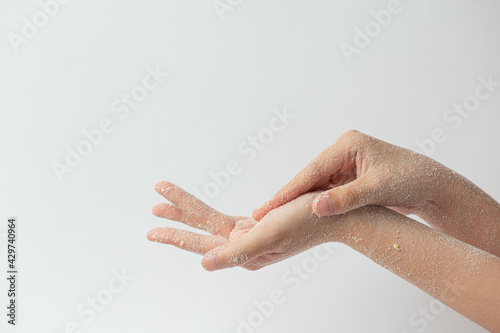 Obraz na plátně Young woman applying natural lemon scrub on hands against white background