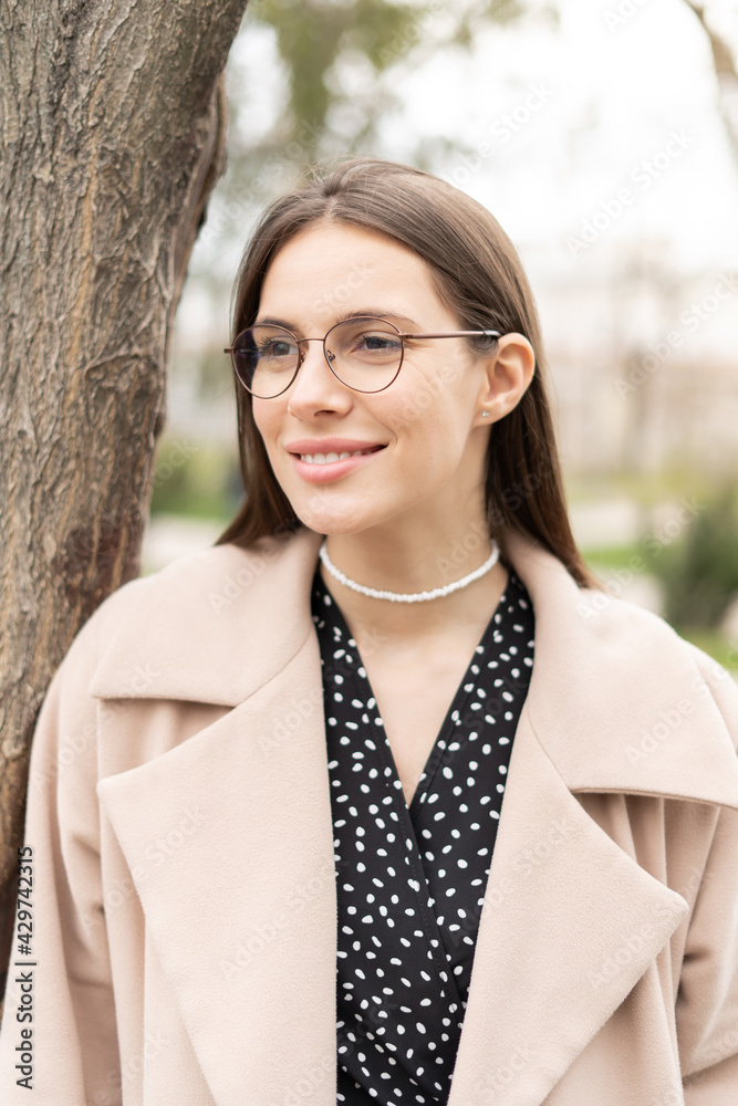 Portrait of a pretty businesswoman wearing eyeglasses looking aside in the park, vertical close up Portrait of a pretty businesswoman wearing eyeglasses looking aside in the park, vertical close up