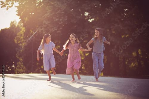 Three little girls spending time in nature. Running and holding hands.