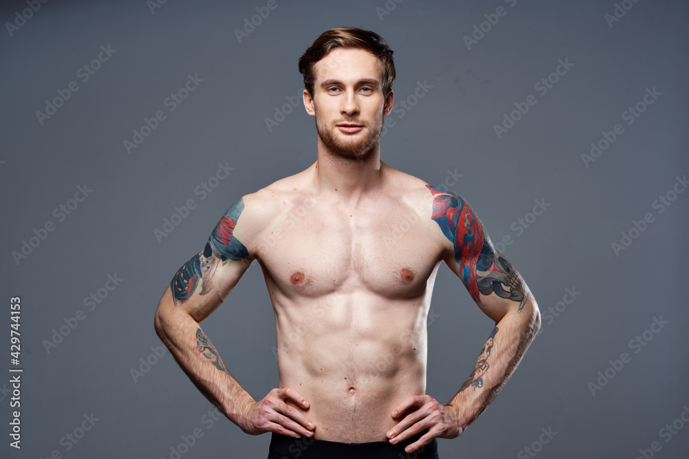 sporty man tattoos on his arms naked torso bodybuilder gray background