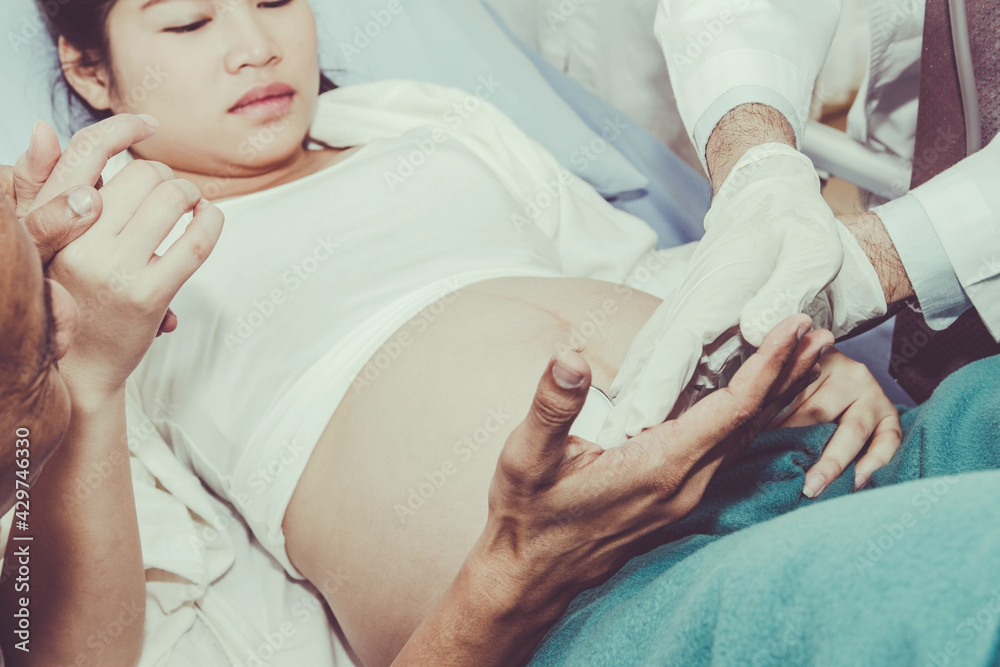 Obraz premium Caring for a pregnant woman by an expert pediatrician is examining the development of a baby in the stomach, with her husband having expectations and being close.