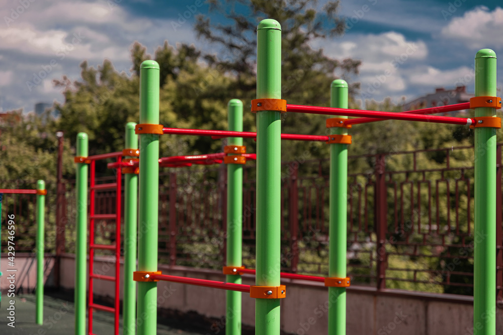 green and red horizontal bars on a playground in the summer
green and red horizontal bars on a playground in the summer