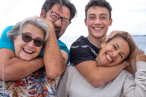 Joyful group of mothers and sons, several generations of the same family, have fun outdoors by the sea. From teenager to grandma © luciano